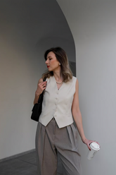 a lady wears a beige vest with grey pants